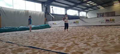 Deux joueuses sur un terrain de beach-volley en salle, pendant un entraînement.