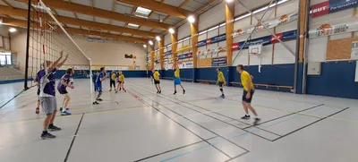 Un joueur en maillot jaune s'élève au filet pour smasher, pendant un match du tournoi.