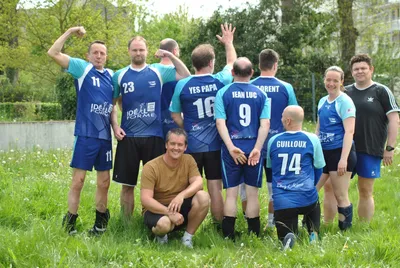 L'équipe visiteuse Idéal Forme pose dans l'herbe après un match, maillots numérotés floqués de surnoms.