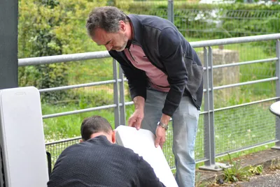 Deux bénévoles installent des tables pliantes à l'extérieur de la salle, avant le début du tournoi.